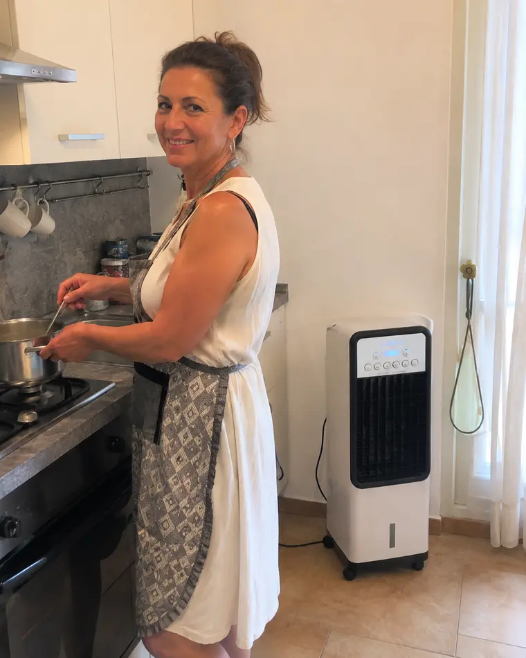 Anna V. cucina ai fornelli con il condizionatore portatile a colonna in cucina