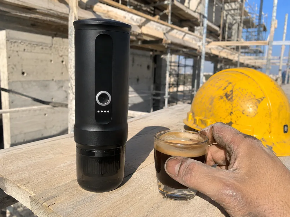 Macchina espresso portatile su un'asse del ponteggio in cantiere accanto al caschetto