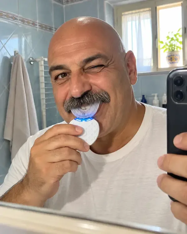 Roberto in bagno, sorridente davanti allo specchio, con lo spazzolino a U in bocca