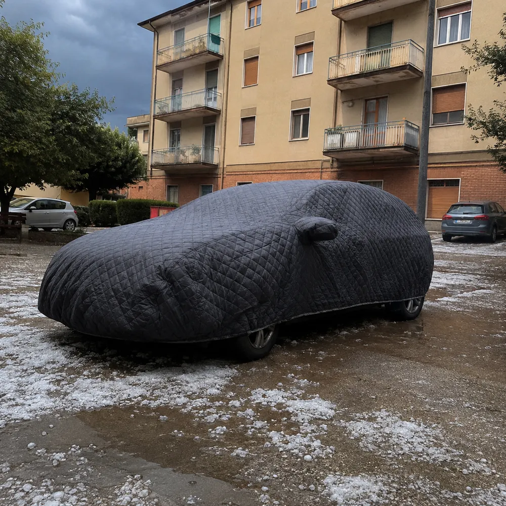 Auto coperta dal telo con la grandine sciolta a terra